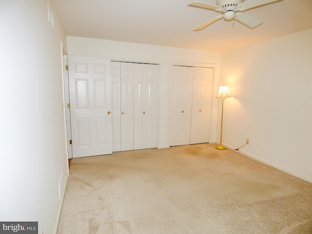 unfurnished bedroom featuring multiple closets, baseboards, and carpet flooring