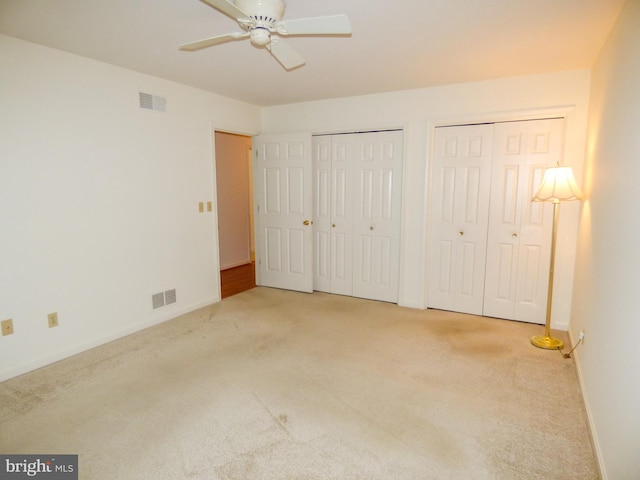 unfurnished bedroom with carpet floors, multiple closets, visible vents, and baseboards