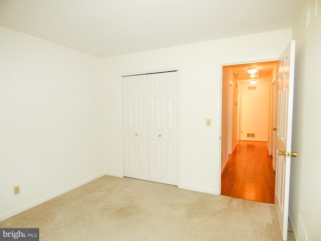 unfurnished bedroom featuring attic access, visible vents, baseboards, a closet, and carpet