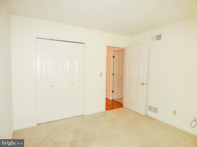 unfurnished bedroom featuring visible vents, carpet, baseboards, and a closet