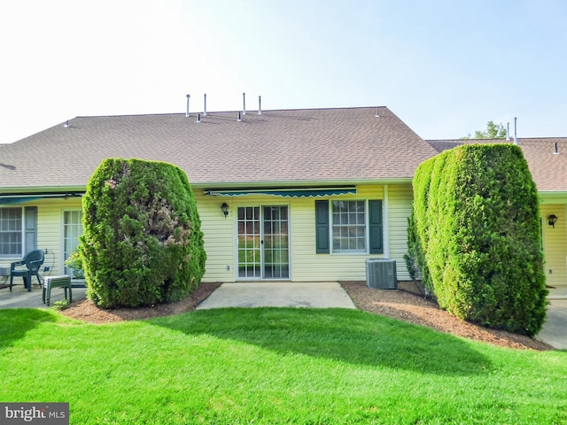 rear view of property with a yard, a patio, central AC unit, and a shingled roof