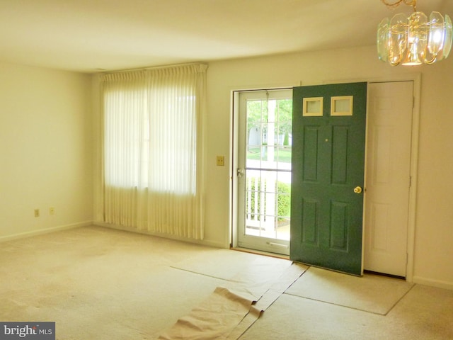 foyer entrance featuring carpet floors, baseboards, and an inviting chandelier