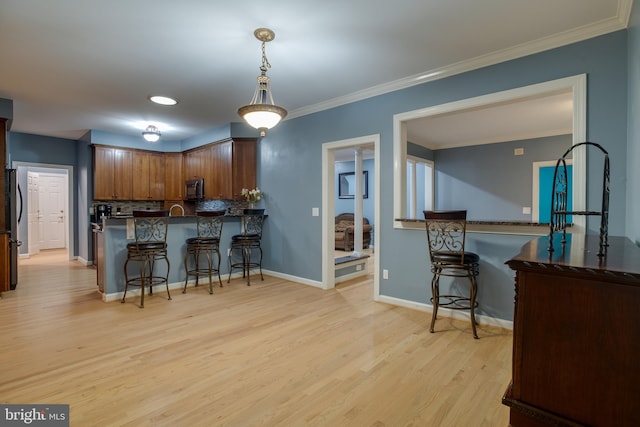 12868 Paddle Wheel Ct, Manassas, VA 20112 - kitchen with a kitchen bar, light wood-type flooring, stainless steel appliances, backsplash, and decorative light fixtures