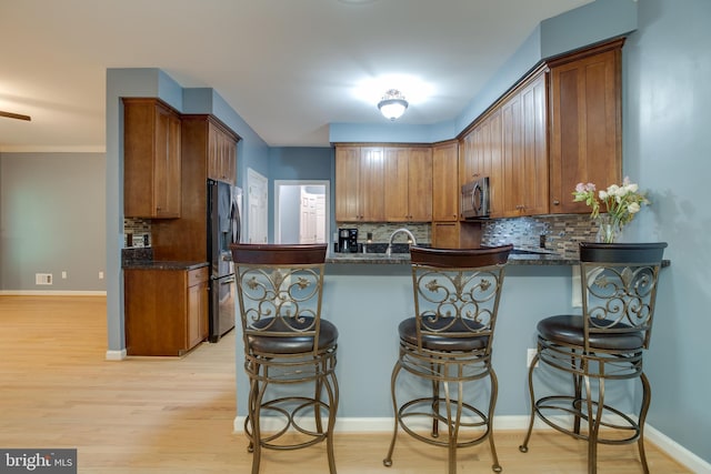 12868 Paddle Wheel Ct, Manassas, VA 20112 - kitchen with appliances with stainless steel finishes, a peninsula, backsplash, and brown cabinets