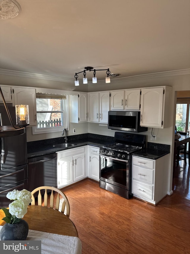 8549 Stonewall Rd, Manassas, VA 20110 - kitchen featuring a sink, crown molding, dark countertops, white cabinets, and appliances with stainless steel finishes