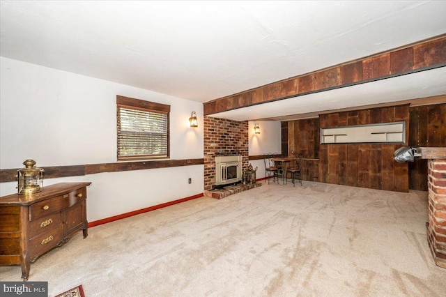living area featuring carpet, baseboards, a fireplace, and wood walls