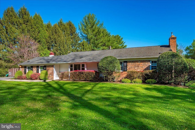 ranch-style home with brick siding, a front lawn, and a chimney