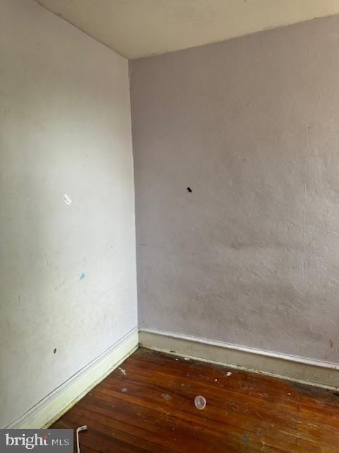 unfurnished room with baseboards and hardwood / wood-style flooring