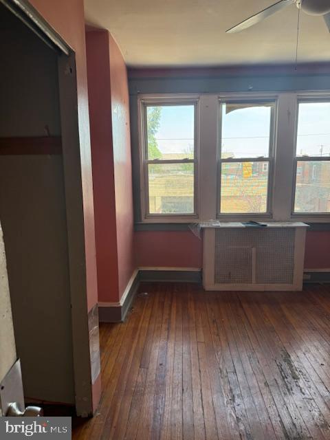 interior space with radiator, ceiling fan, baseboards, and hardwood / wood-style flooring
