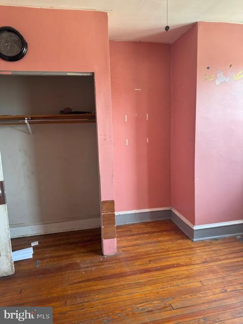 unfurnished bedroom with baseboards, hardwood / wood-style flooring, and a closet