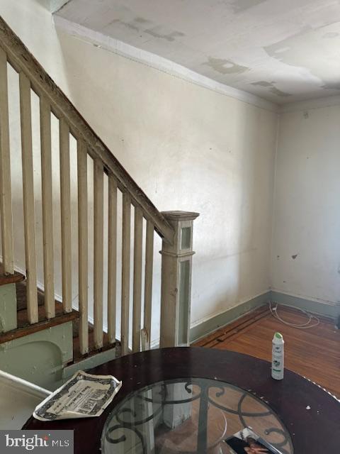 stairway with baseboards, crown molding, and wood finished floors