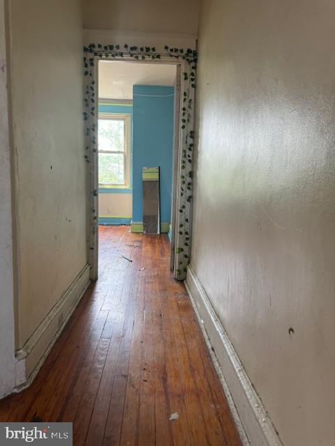 hall with wood-type flooring and baseboards