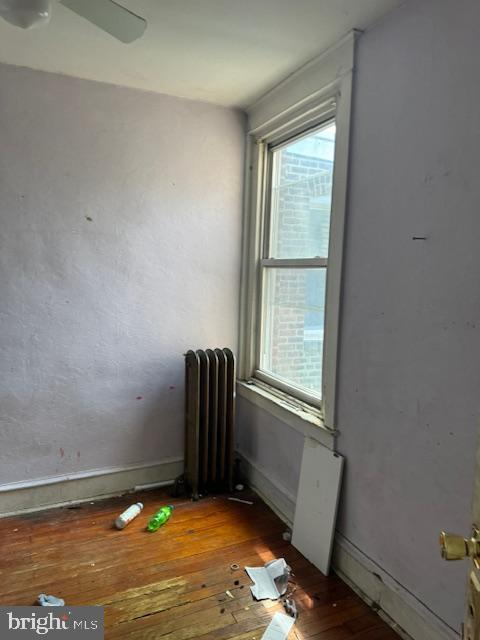 unfurnished room with radiator, baseboards, and hardwood / wood-style floors