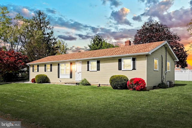 single story home featuring fence, a chimney, a shingled roof, central AC unit, and a yard