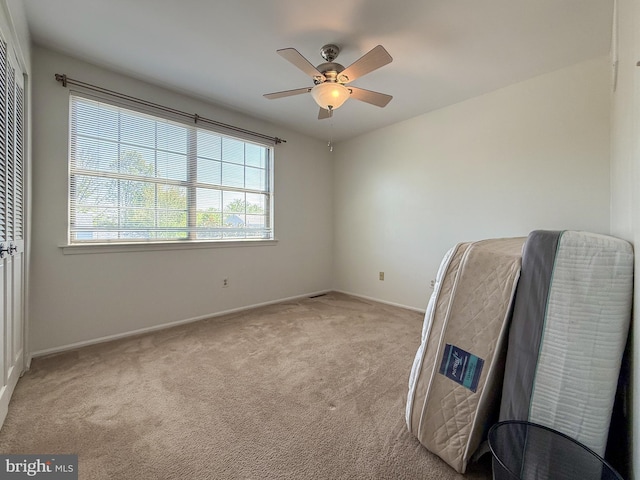 spare room featuring baseboards, light carpet, and ceiling fan
