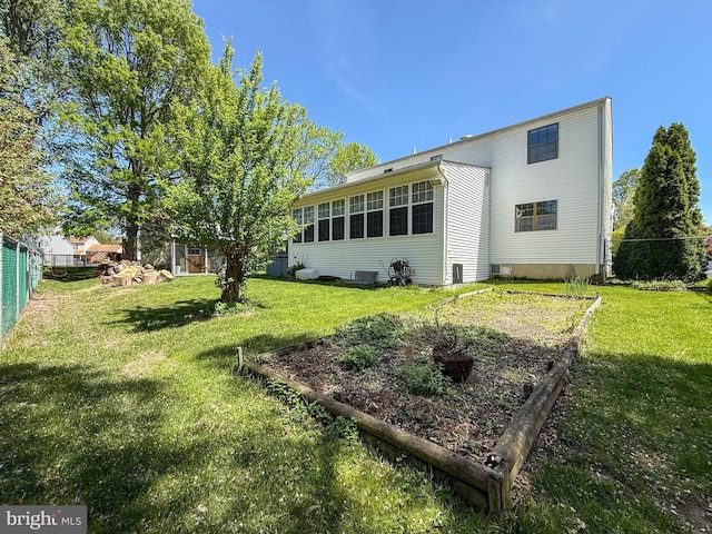 back of property featuring a lawn, central AC, and fence