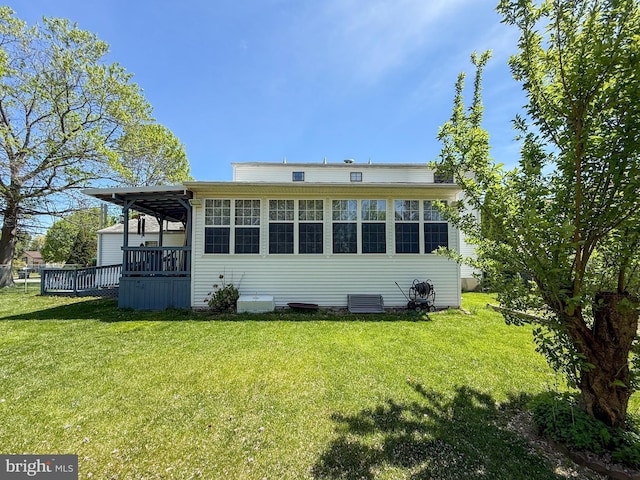 rear view of property featuring a lawn and a wooden deck