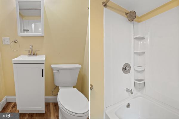 bathroom with vanity, shower / bathtub combination, wood finished floors, and toilet