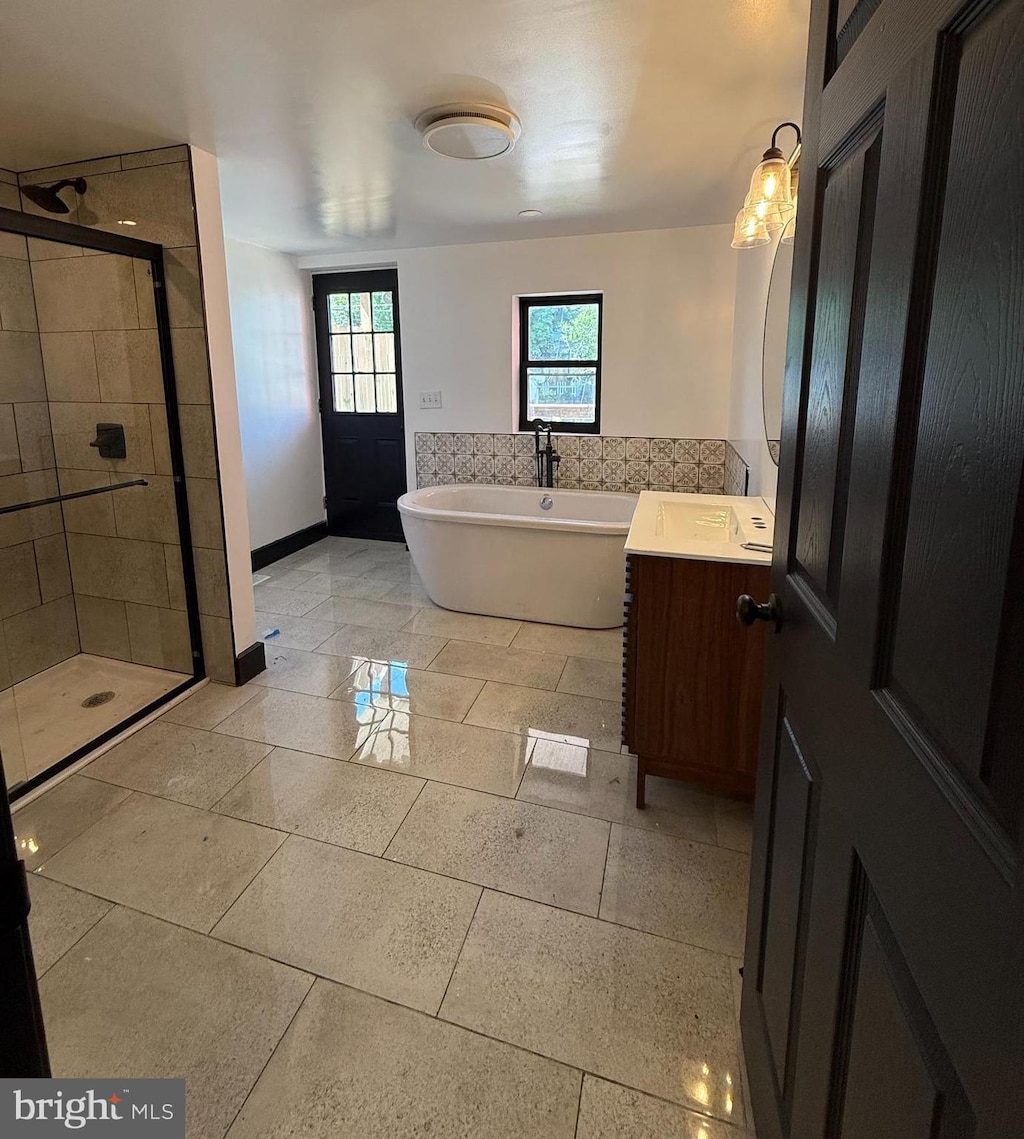 bathroom with vanity, baseboards, a freestanding bath, and a stall shower