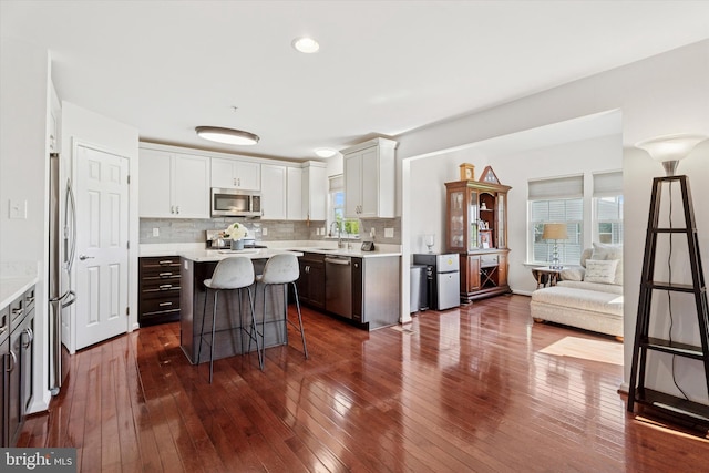 kitchen with open floor plan, appliances with stainless steel finishes, a breakfast bar, and light countertops