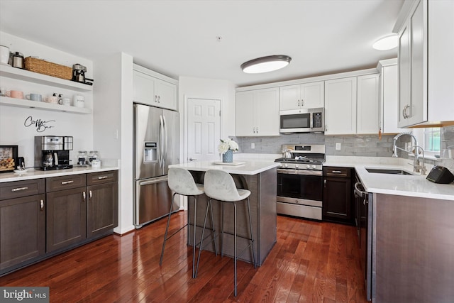 kitchen with a breakfast bar, dark wood-style floors, light countertops, a sink, and appliances with stainless steel finishes