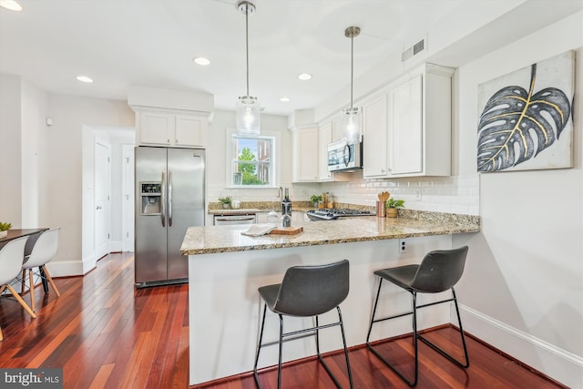 519 Somerset Pl NW, Washington, DC 20011 - kitchen featuring appliances with stainless steel finishes, a peninsula, baseboards, white cabinets, and backsplash