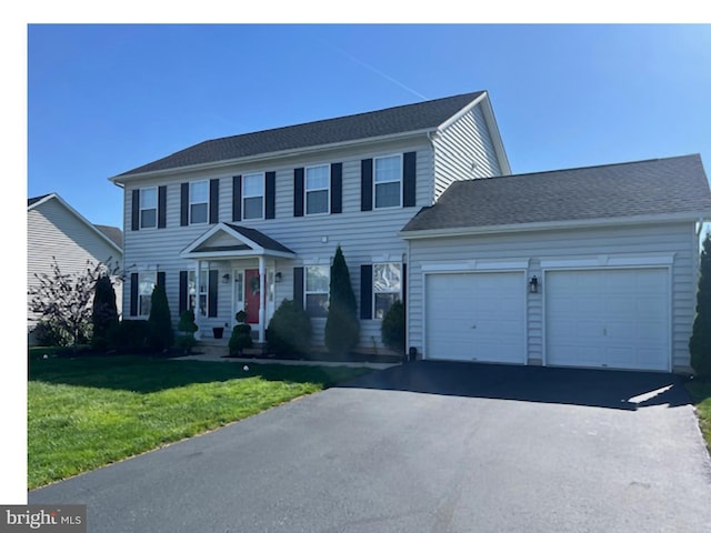 colonial home with an attached garage, a front yard, and aphalt driveway