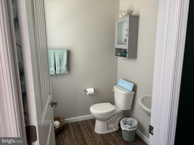 half bath featuring baseboards, toilet, and wood finished floors