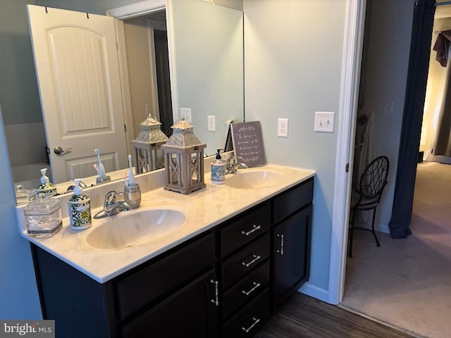 full bath with double vanity, a sink, and wood finished floors