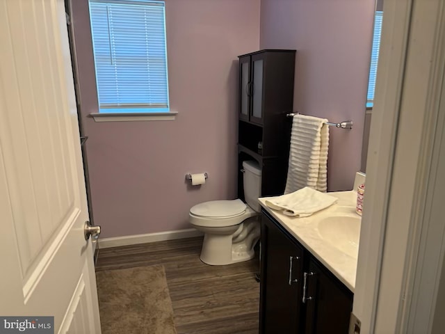bathroom featuring baseboards, vanity, toilet, and wood finished floors