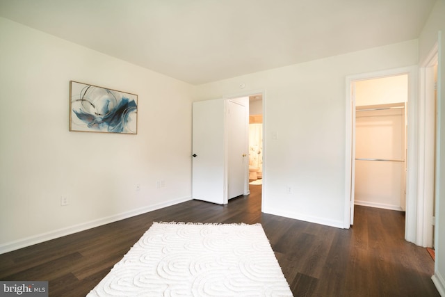 8607 Beekman Pl Unit 7B, Alexandria, VA 22309 - unfurnished bedroom featuring dark wood-style floors, a walk in closet, and baseboards