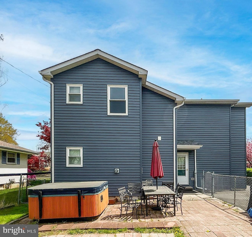 rear view of house with a fenced backyard, a hot tub, and a patio area