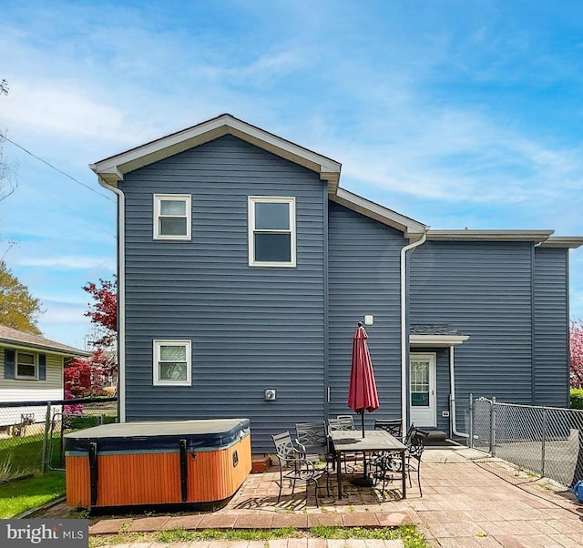 rear view of house with a fenced backyard, a hot tub, and a patio area