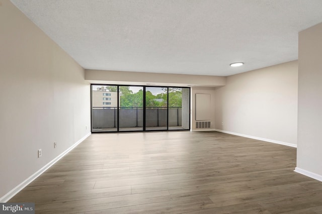 spare room with baseboards, visible vents, and wood finished floors