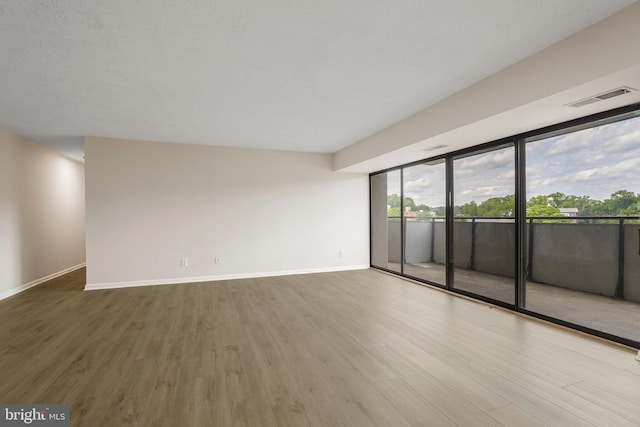 unfurnished room with visible vents, baseboards, and wood finished floors