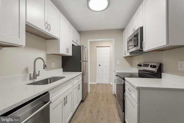 kitchen featuring a sink, white cabinets, stainless steel appliances, and light wood finished floors