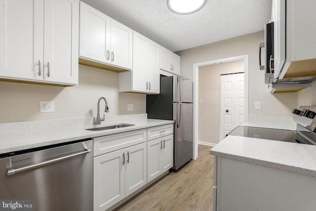 kitchen with white cabinetry, light stone counters, a sink, light wood finished floors, and appliances with stainless steel finishes