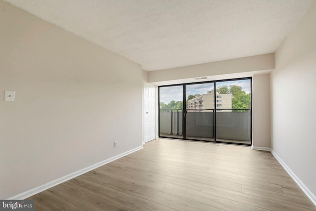empty room with baseboards, a textured ceiling, and wood finished floors