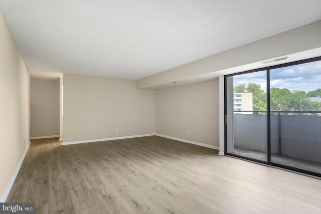 empty room with visible vents, baseboards, and wood finished floors