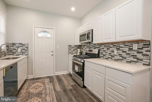 kitchen with tasteful backsplash, a sink, stainless steel appliances, white cabinetry, and dark wood-type flooring