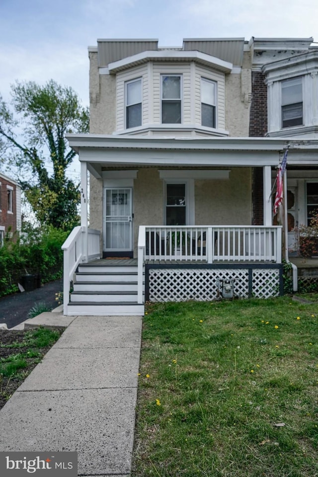 view of front of home featuring a porch, a front yard, and stucco siding
