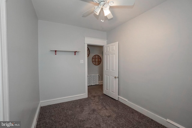 carpeted spare room with radiator, baseboards, and a ceiling fan
