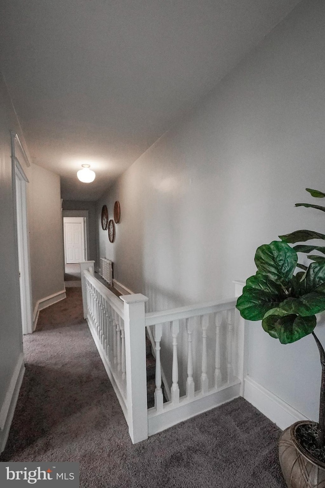 corridor with baseboards, carpet, and an upstairs landing