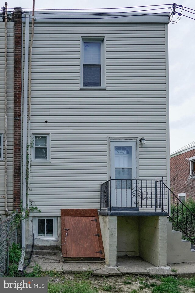 rear view of property featuring stairway and fence