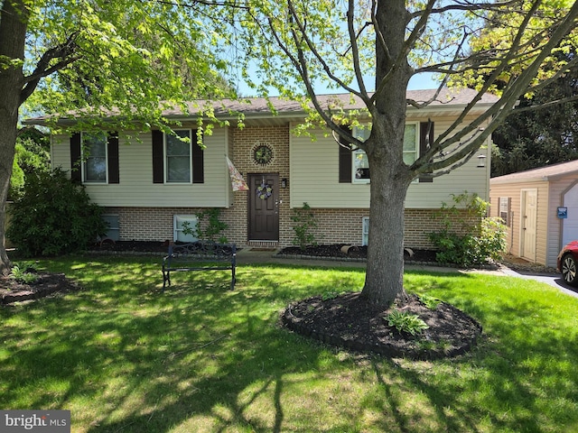 raised ranch featuring brick siding and a front lawn