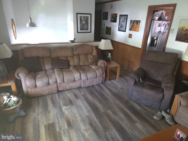 living area with wooden walls, visible vents, wainscoting, and wood finished floors