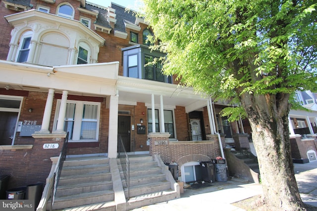 townhome / multi-family property featuring brick siding and covered porch