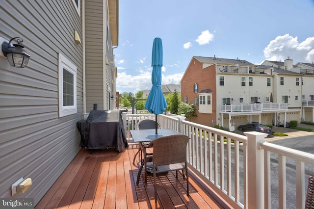 deck with outdoor dining space, a grill, and a residential view