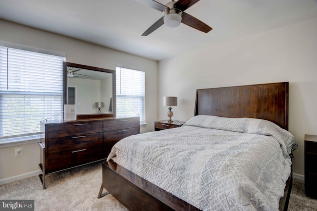 bedroom featuring light colored carpet, baseboards, and a ceiling fan