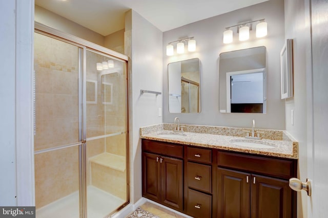 bathroom with a shower stall and double vanity